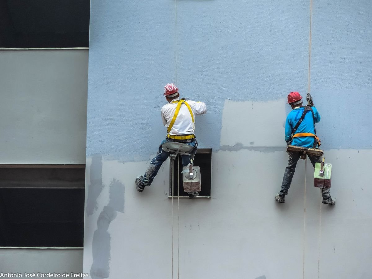 Commercial painters on ropes painting a building facade