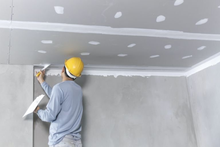 Drywall finisher applying joint compound to a ceiling