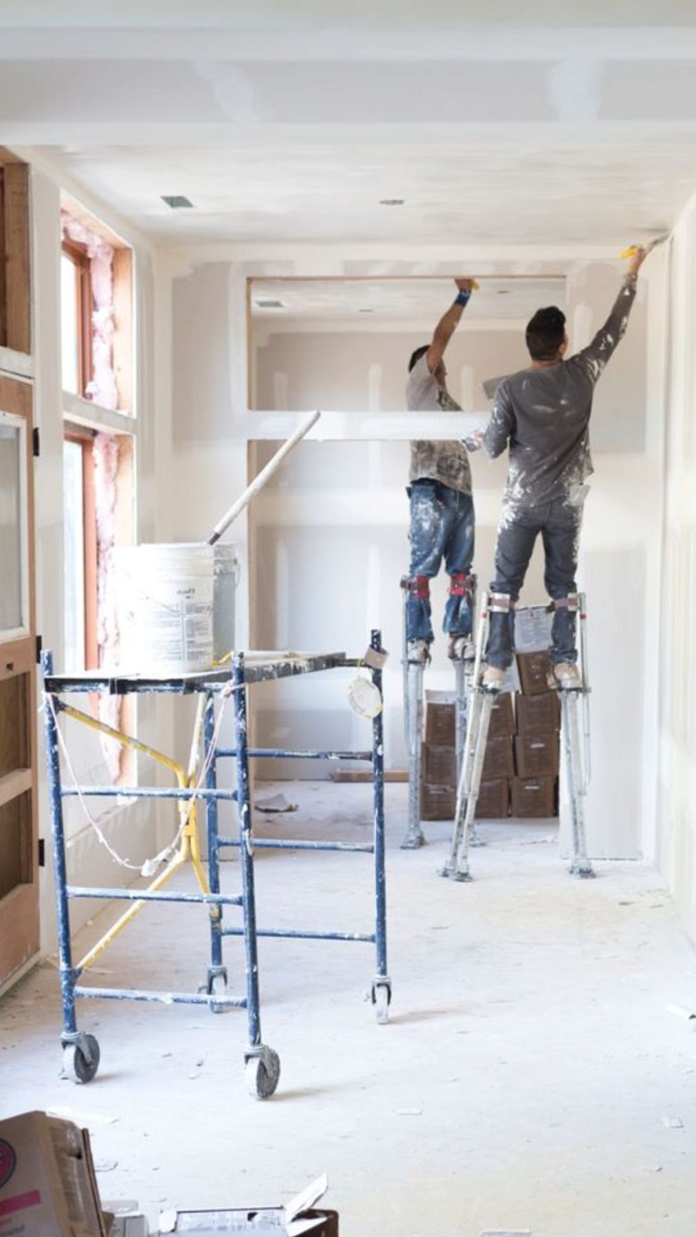 Finishers on stilts completing walls and ceilings in a new interior